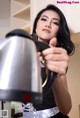 A woman in a black dress holding a silver kettle.