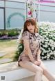 A woman sitting on a bench in front of a flower garden.