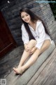 A woman sitting on a stone ledge with her legs crossed.