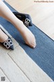 A woman's feet on a rug with a pair of black shoes.