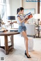 A woman standing in a living room holding a magazine.