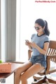 A woman sitting on a chair looking at her phone.