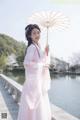 A woman in a pink dress holding an umbrella.