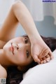 A woman laying on a bed with her hand on her head.