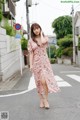 A woman in a pink floral dress is walking down the street.