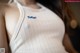 A woman wearing a white tank top with a blue logo on it.