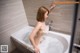 A naked woman taking a bath in a bathtub.