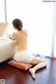 A woman sitting on a pillow in front of a window.