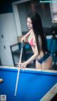 A woman in a bikini playing pool.