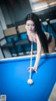 A woman in a bikini playing pool with a cue.