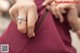 A woman in a maroon dress holding a diamond ring.