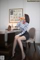 A woman sitting at a desk drinking from a glass.