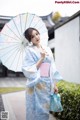 A woman in a blue kimono holding an umbrella.