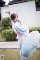 A woman in a blue kimono holding a blue umbrella.