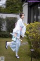 A woman in a blue kimono holding an umbrella.