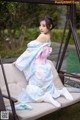 A woman in a blue and pink kimono sitting on a swing.