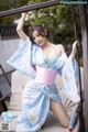 A woman in a blue and pink kimono posing on a swing.