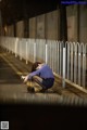 A woman sitting on the side of a road looking at her cell phone.