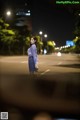 A woman standing in the middle of a street at night.