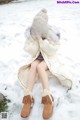 A woman sitting in the snow wearing a coat and hat.