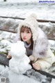 A woman sitting on a train track next to a snowman.