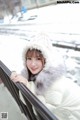 A woman in a white coat and hat leaning on a railing.