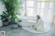 A woman sitting in a bathtub next to a potted plant.