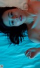 A woman laying on top of a bed in a blue light.