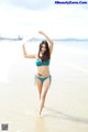 A woman in a blue bikini standing in the water.