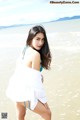 A woman in a white dress standing on a beach.