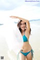 A woman in a blue bikini standing in the water.