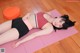 A woman laying on a pink yoga mat on a wooden floor.