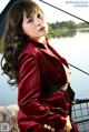 A woman in a red velvet jacket posing on a boat.