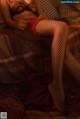 A woman in fishnet stockings sitting on a bed.