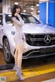 A woman in a silver dress standing next to a white car.