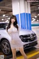 A woman in a silver dress standing next to a car.