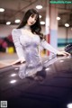 A woman in a silver dress standing next to a car.