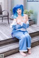 A woman with blue hair sitting on a wooden deck.