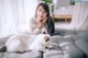 A woman laying on a bed with a white cat.