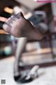 A woman's feet in black pantyhose sitting on a chair.