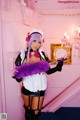 A woman in a maid outfit holding a purple feather boa.