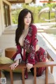 A woman in a red dress sitting on a wooden bench.