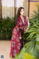 A woman in a red dress standing next to a palm tree.