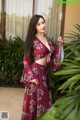 A woman in a red floral dress posing for a picture.