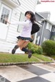 A young woman in a school uniform jumping in the air.