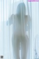 A nude woman standing in front of a white curtain.