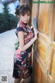 A woman in a cheongsam leaning against a wooden door.