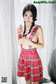 A woman in a red and black plaid dress posing for a picture.