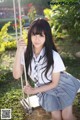 A woman in a school uniform sitting on a swing.