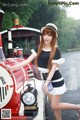 A woman in a black and white dress and hat standing next to a train.